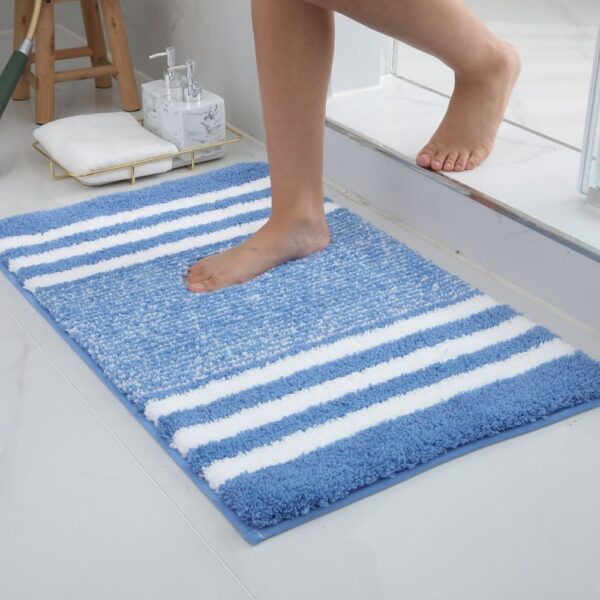 Blauw gestreept badkamer vloerkleed met voeten erop.