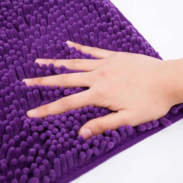 Paarse chenille badmat 60x90cm met optimale absorptie, hand op oppervlak.