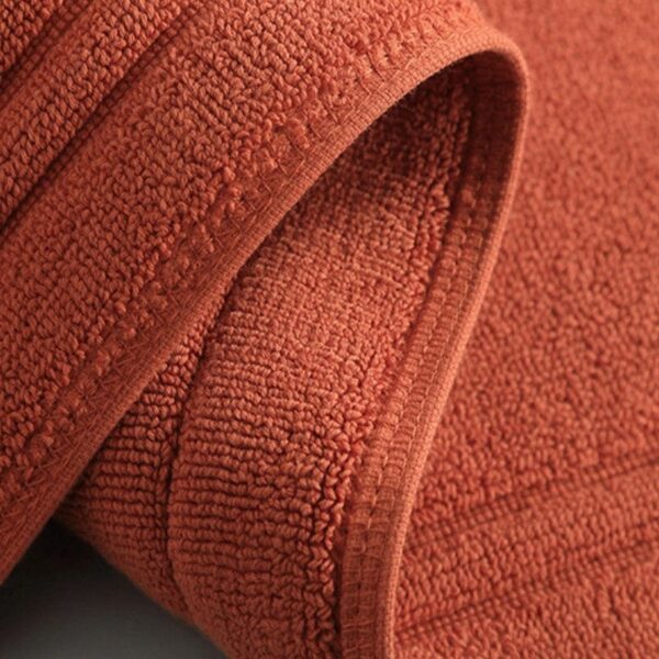 Dikke katoenen badmat in warme terracotta kleur, zacht en absorberend.