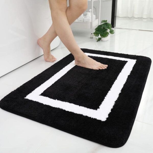 Grote absorberende badkamermat met witte rand, zwart-wit design.