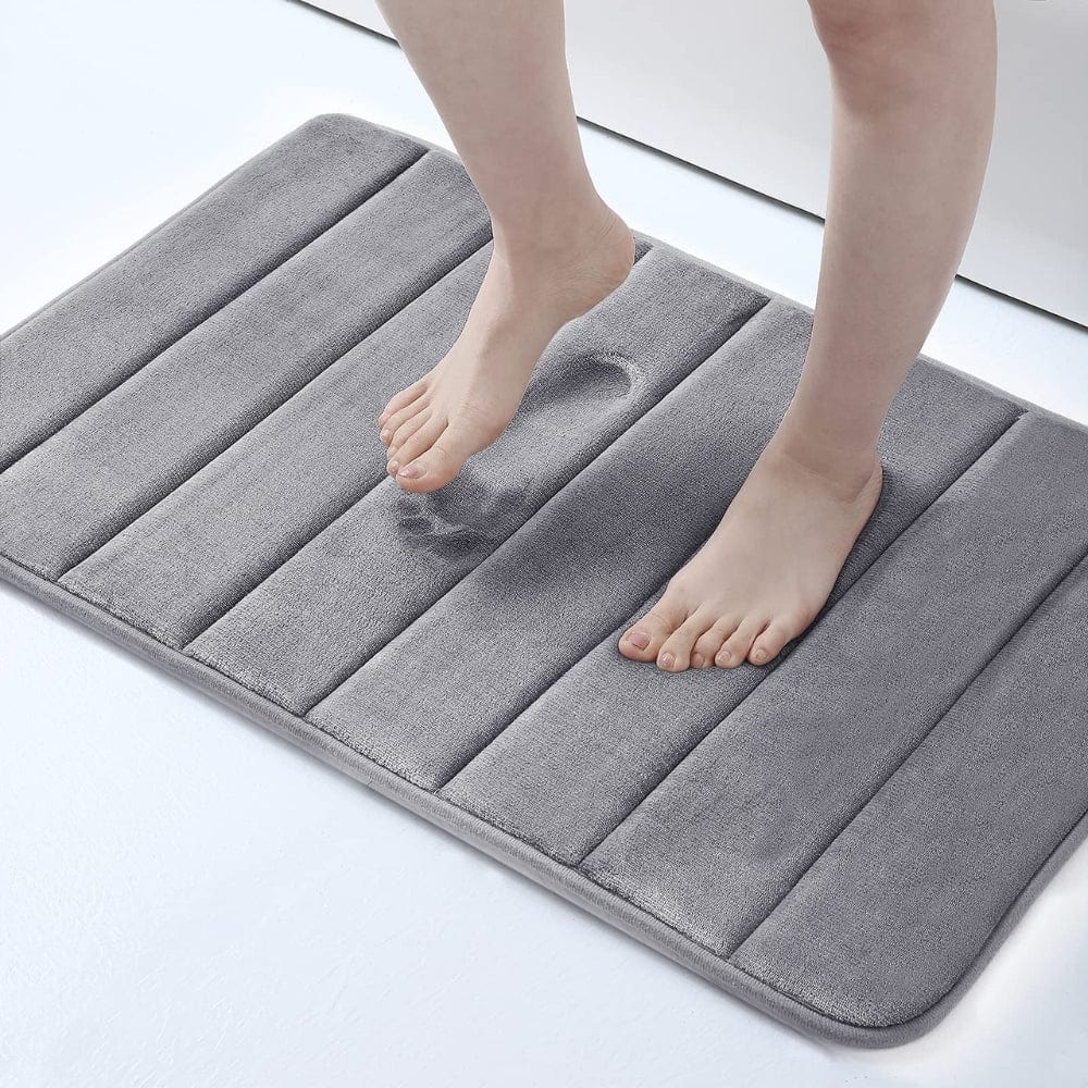 Grijze ultra-absorberende badmat met voeten erop.