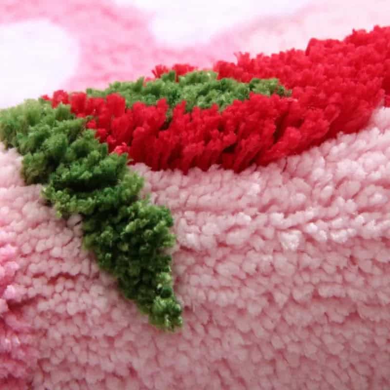 Aardbei badmat met rood groen fruitmotief op roze fluweel.
