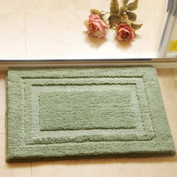 Groene absorberende badmat voor badkamer met randdetail.