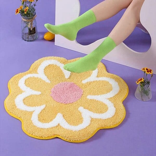 Bloemvormige badkamermat met gele bloem en witte rand.