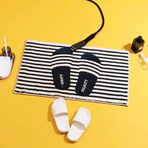 Gestreepte badmat met slippers en badaccessoires op gele achtergrond.