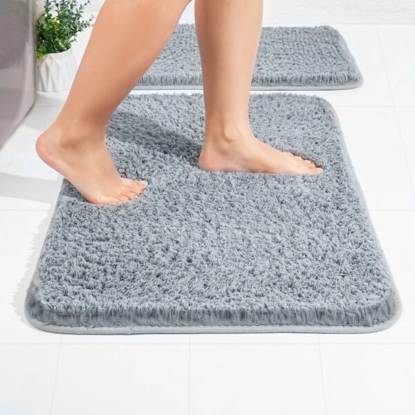 Grijze microvezel badkamer tapijt met voeten erop.
