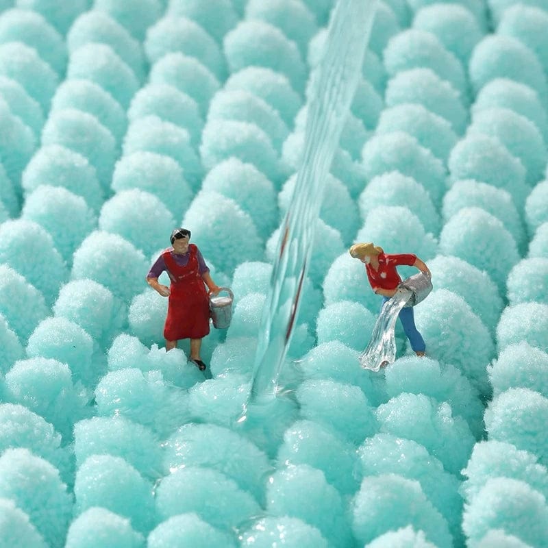 Turquoise badmat met mini figuurtjes en waterstroom.