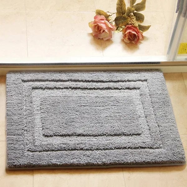 Gray absorbent bath mat with textured border for bathroom.