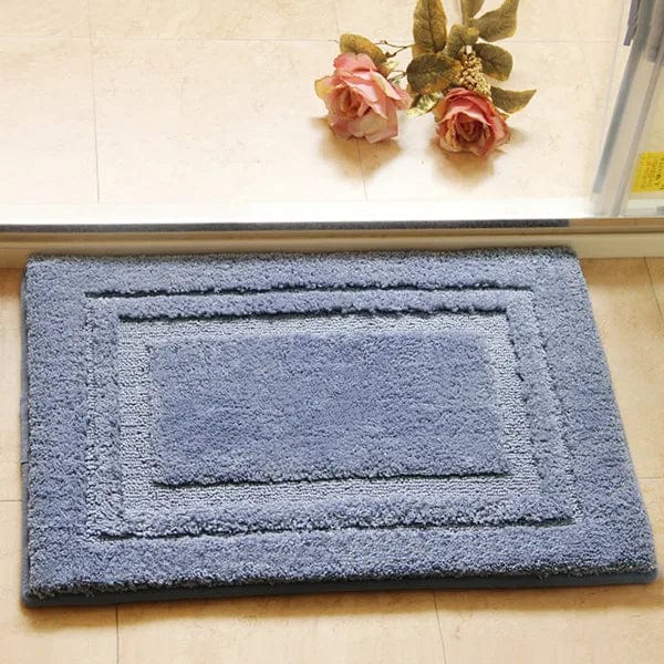 Absorbent blue bath mat with textured border for bathroom.