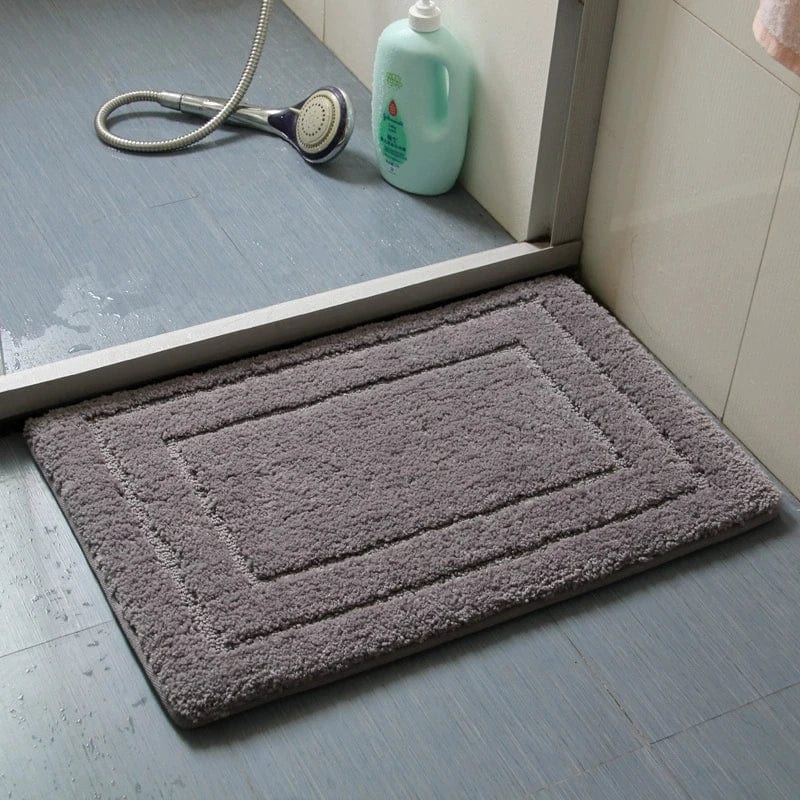 Absorbent grey bath mat with border design near shower.