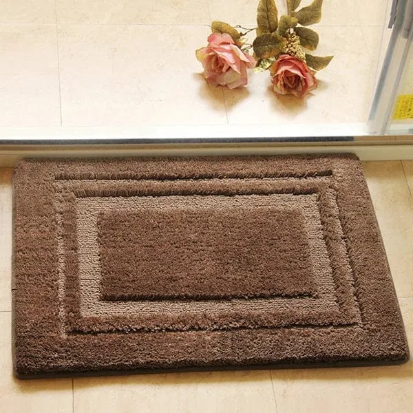 Absorbent brown bath mat with textured border design.