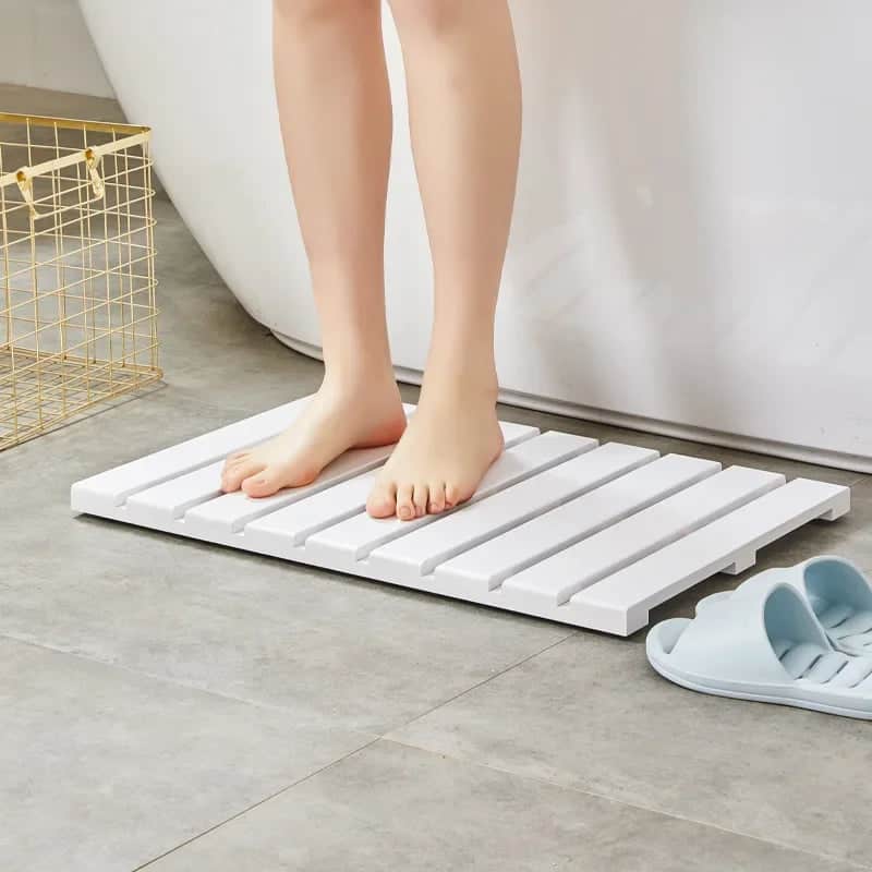 White bamboo slatted bath mat for bathroom comfort and drainage.