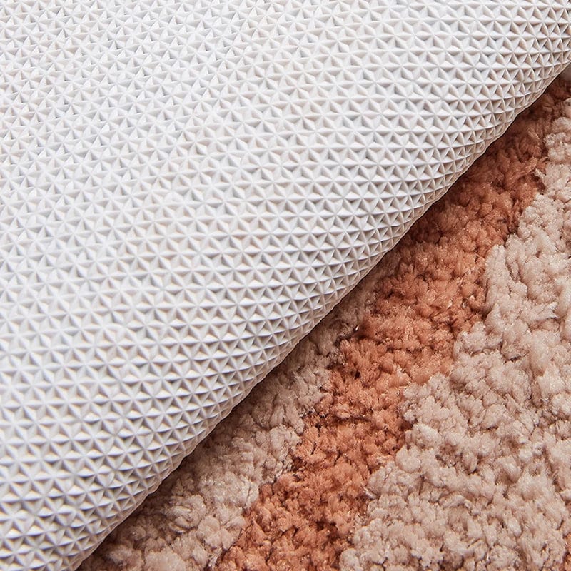 White textured bath mat with geometric pattern on soft beige rug.