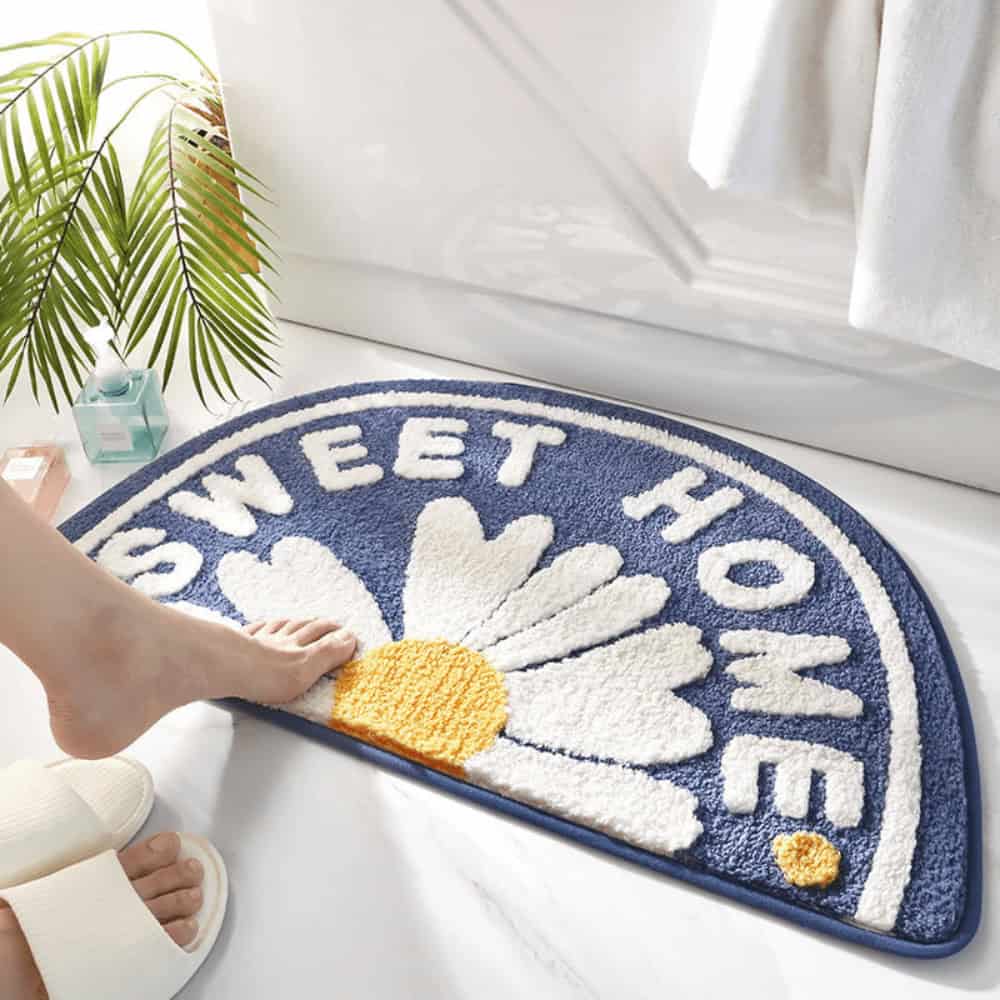 Half circle bath mat with 'Sweet Home' and daisy design.