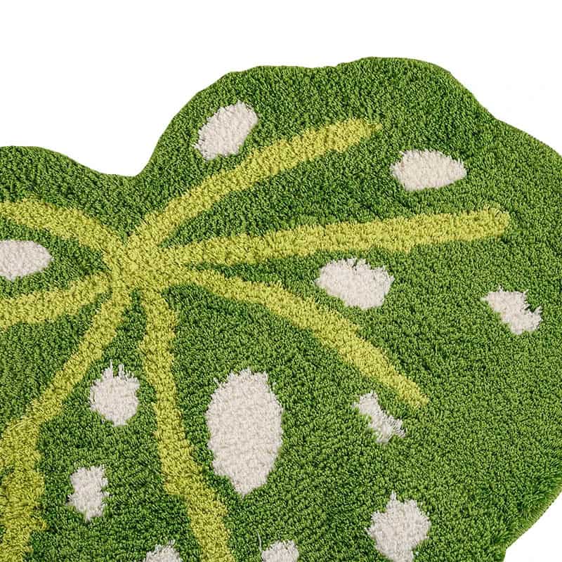 Green leaf-shaped bath mat with white spots and yellow veins.