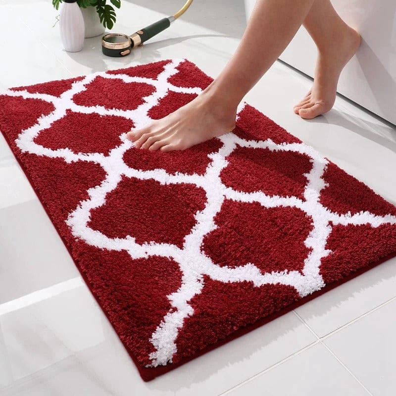 Red and white Berber bath mat with geometric pattern, foot stepping on plush surface.