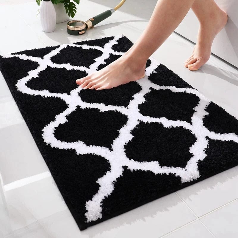 Black and white Berber bath mat with geometric pattern, foot stepping on it.