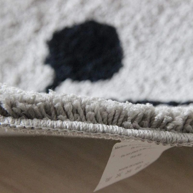 Cat-themed bath mat with black eye detail and textured fringe.