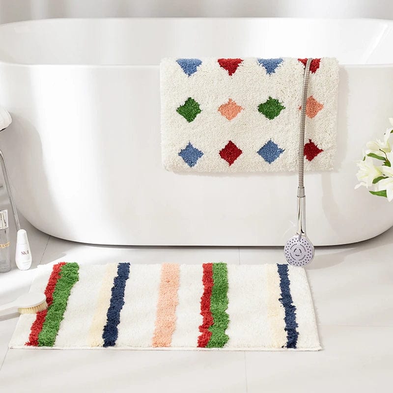 Colourful striped bath mat with diamond pattern towel hanging on bathtub.