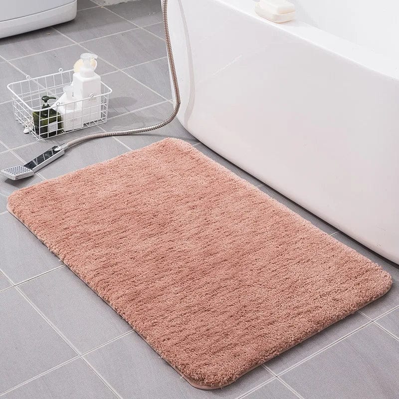 Soft fluffy pink bath mat beside white bathtub.