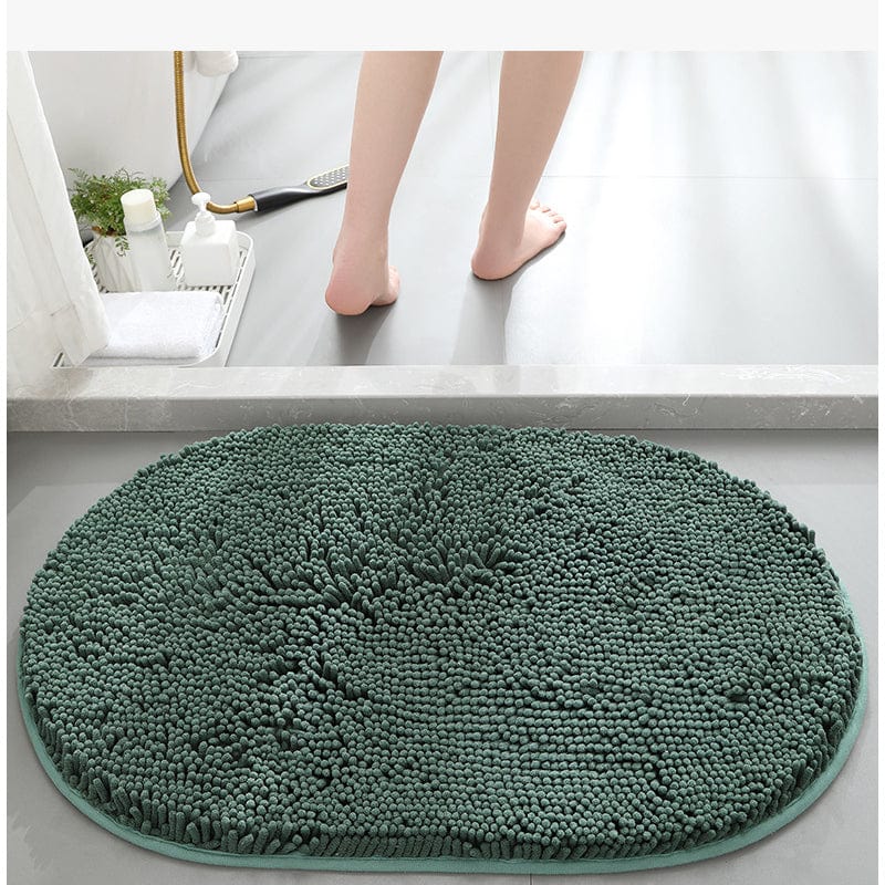 Dark green oval bath mat with textured loops for comfort and grip.