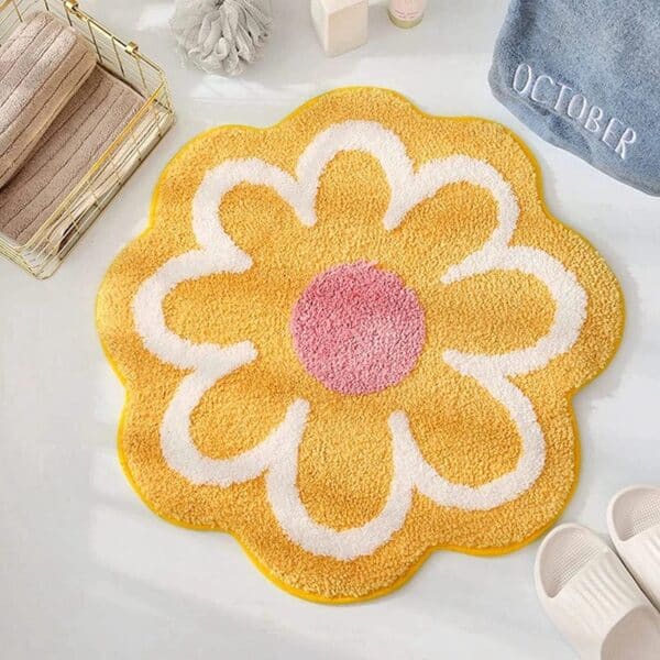 Flower shaped bath mat with yellow petals and pink center.