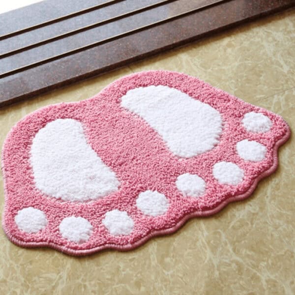 Pink foot-shaped bath mat with white toe and heel accents.