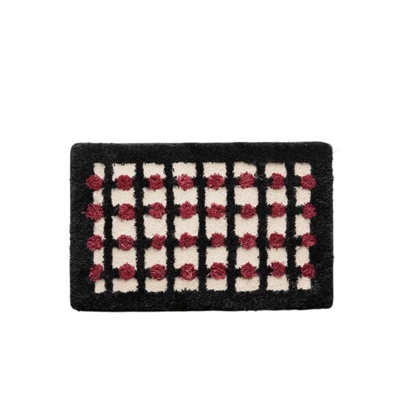 Geometric bath mat with black and red pom-pom pattern.