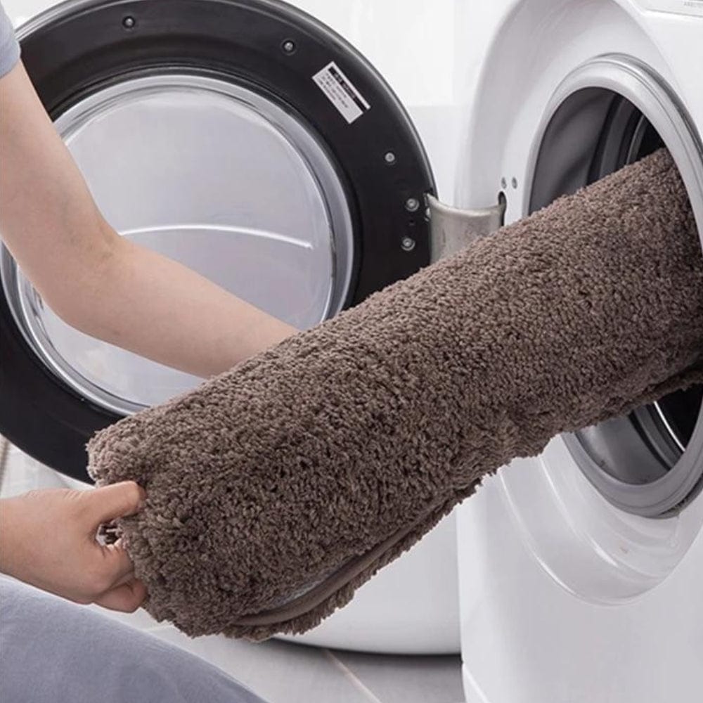 Grey non-slip bath mat being washed in washing machine.