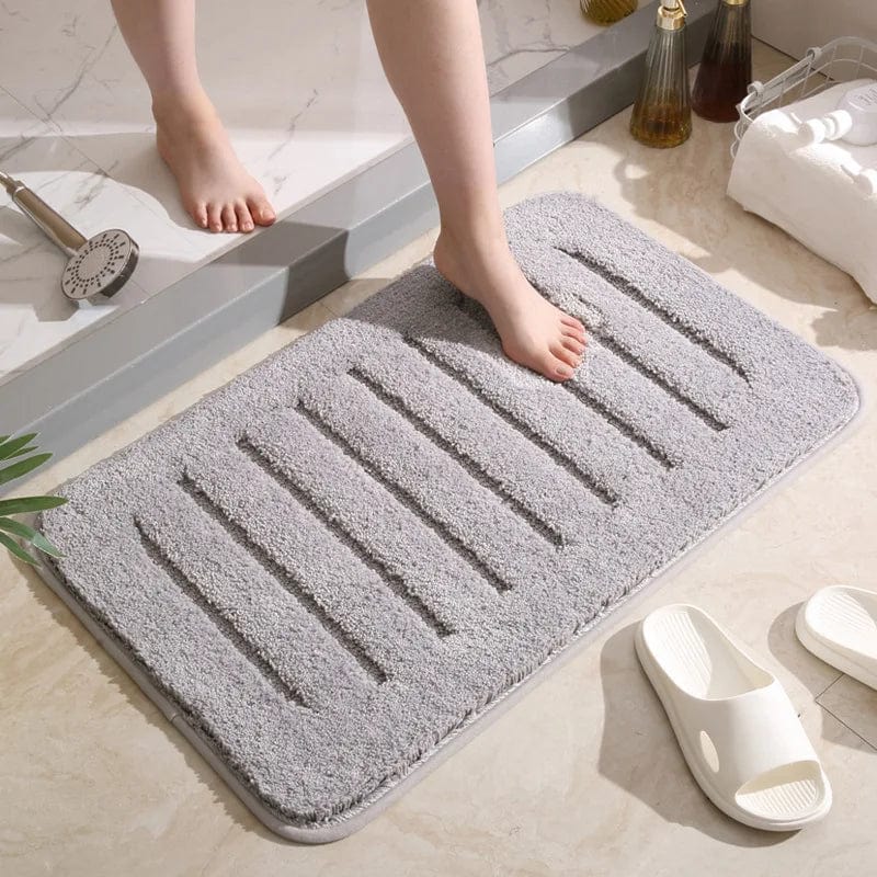 Grey microfiber bath mat with drainage grooves for bathroom comfort and dryness.