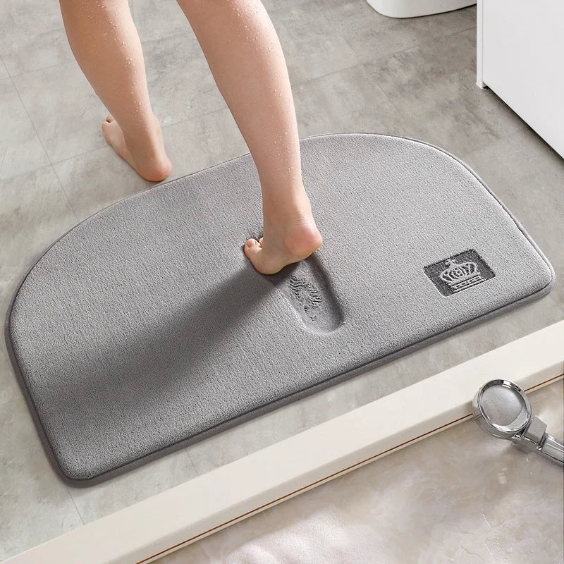 Gray halfmoon bath mat with crown logo, footprints visible, non-slip bathroom rug.
