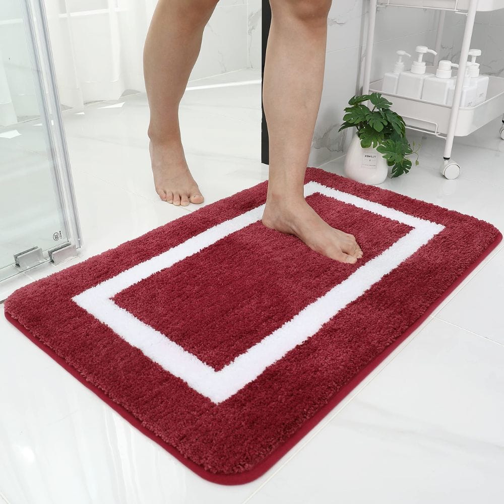 Large red absorbent bath mat with white border for bathroom comfort.