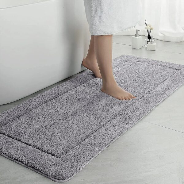 Large grey fluffy bath mat with person stepping on it near bathtub.