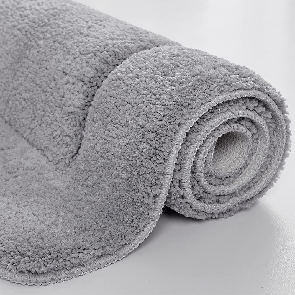 Large grey fluffy bath mat rolled up, soft texture, bathroom rug.