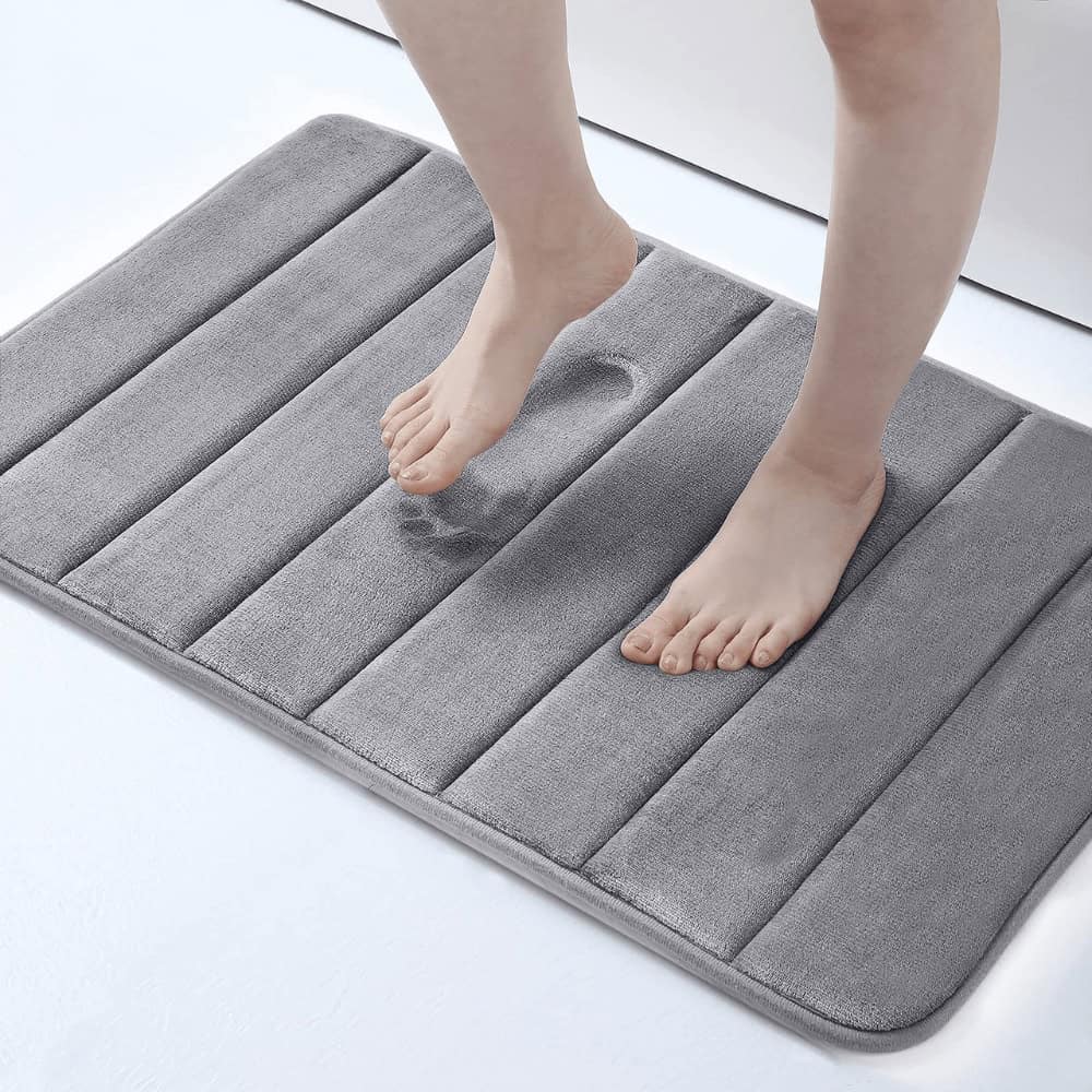 Large fluffy grey bath mat with feet stepping on it for comfort and style.