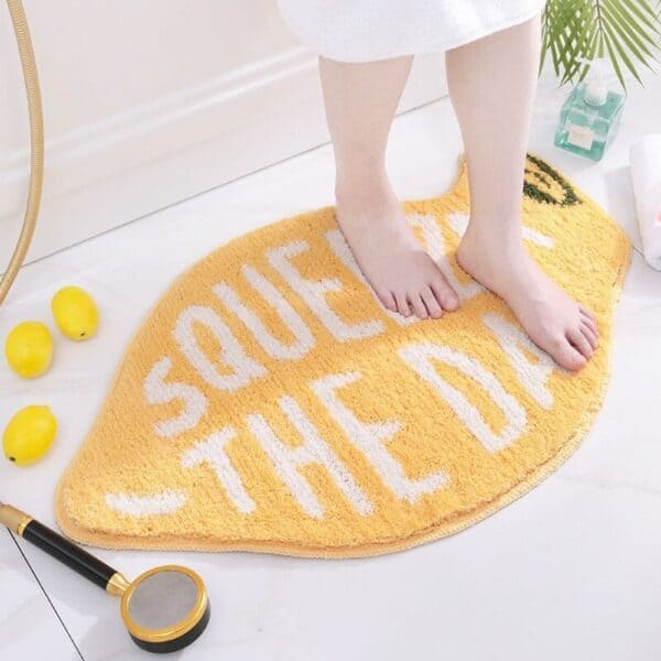 Lemon-shaped bath mat with 'SQUEEZE THE DAY' text, cozy bathroom decor.