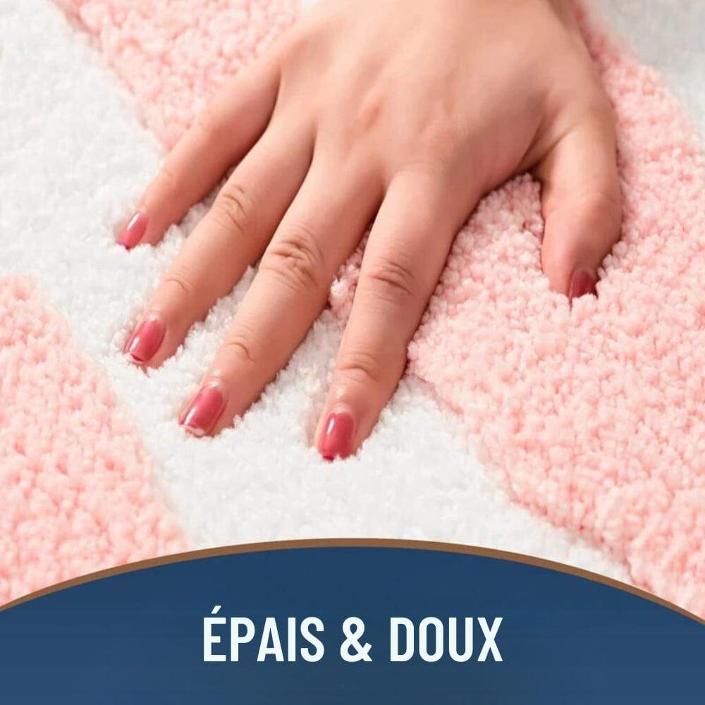 Soft pink and white plush bath mat with hand resting on it, thick and cozy.