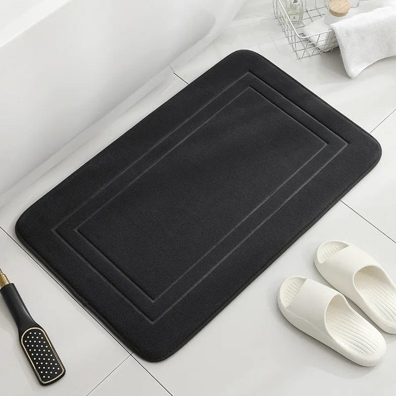 Black memory foam bath mat for comfort and grip near bathtub.
