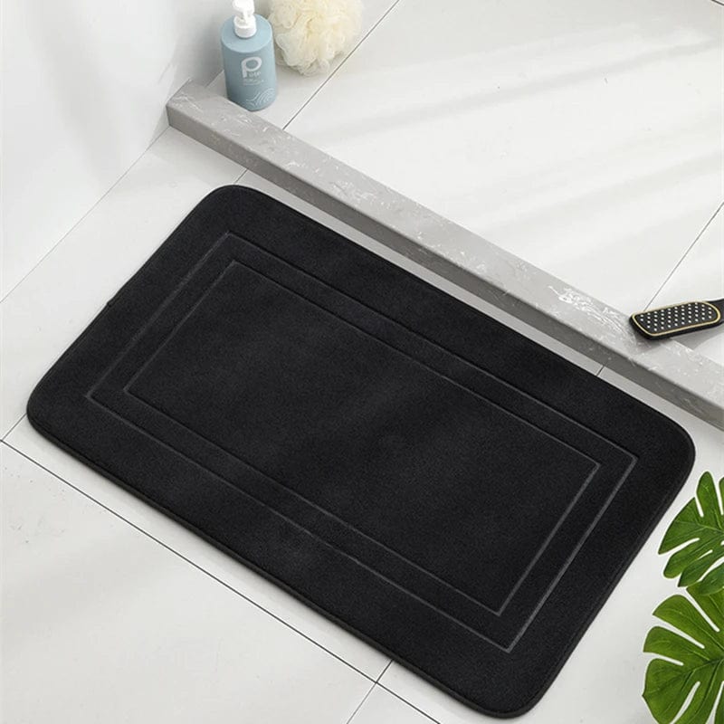 Black memory foam bath mat for comfort and grip in modern bathroom.
