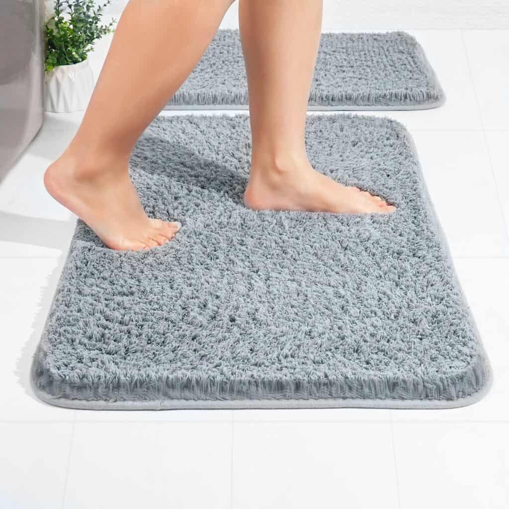 Gray microfiber bath mat with feet stepping on it for comfort and non-slip bathroom safety.