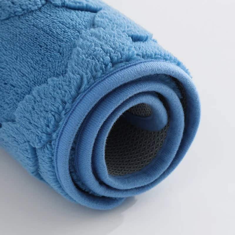 Blue microfibre bath mat rolled up showing soft texture and non-slip backing.