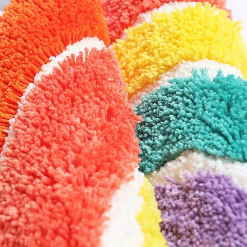 Multicoloured fluffy bath mat with rainbow pattern.