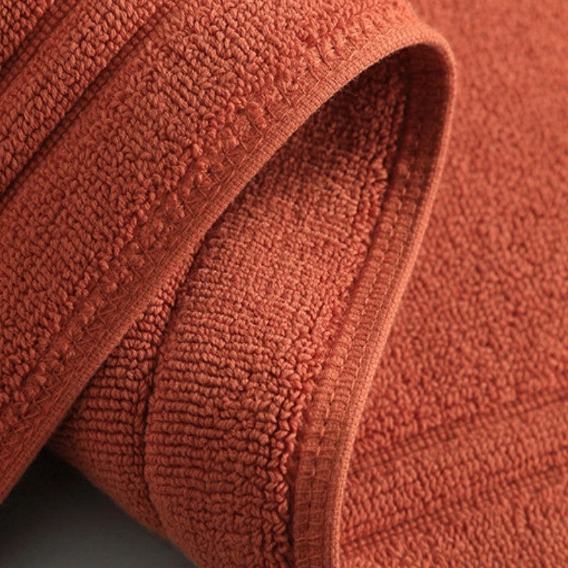 Non-slip cotton bath mat, terracotta color, textured towel for bathroom safety.