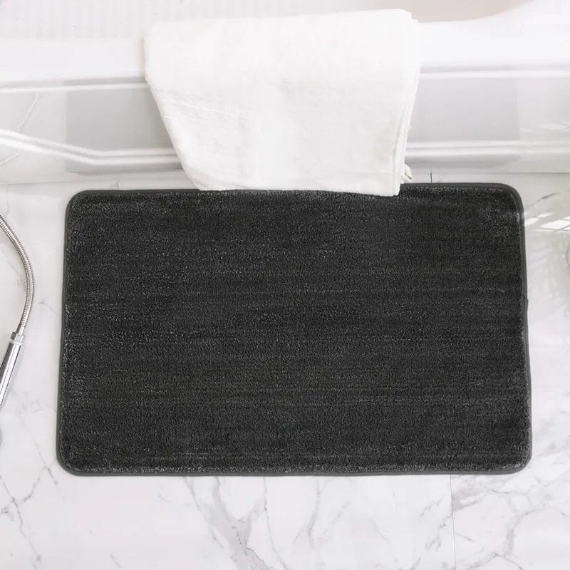Black non-slip bath mat for bathroom safety on marble floor.