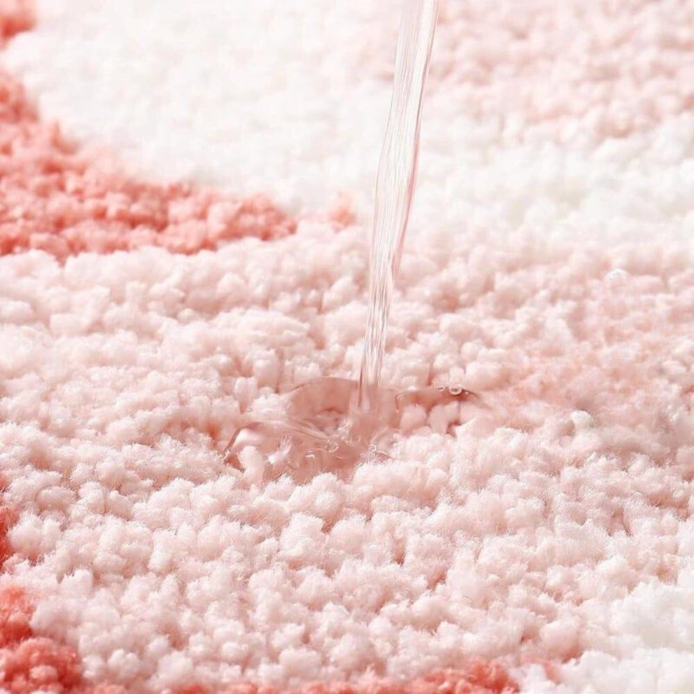 Pink and white fluffy bath mat absorbing water.