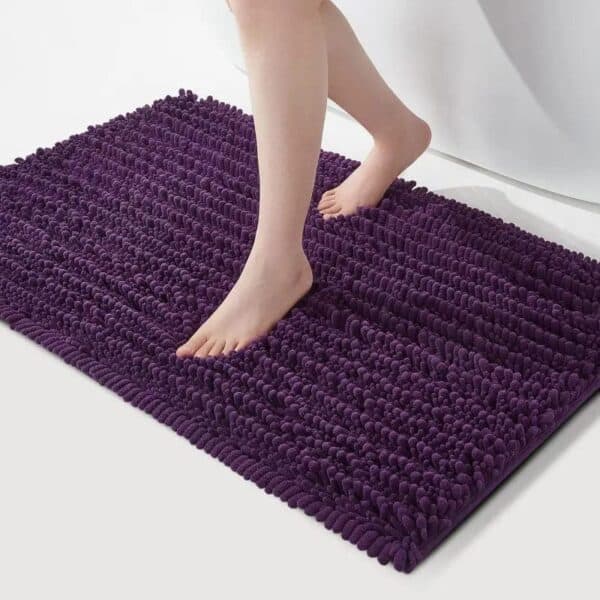 Purple shaggy bath mat with feet stepping on it for comfort and style.