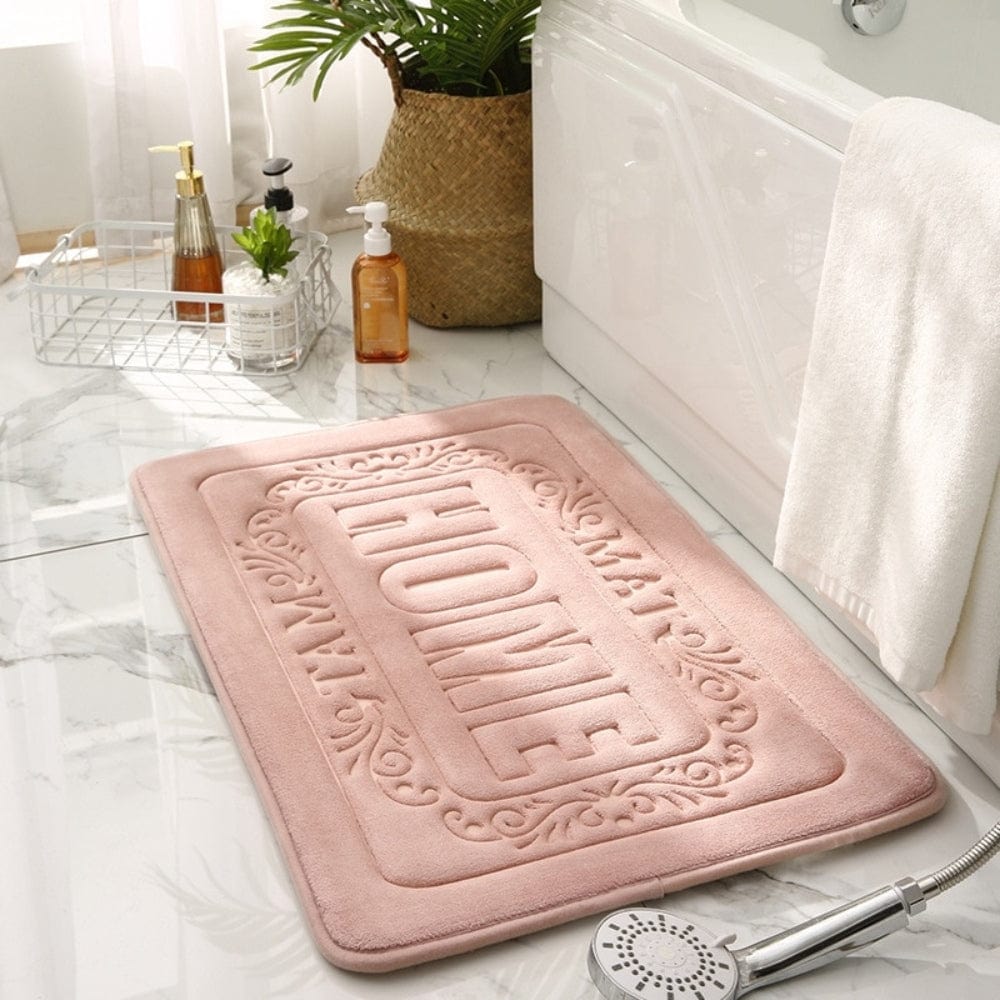 Pink rectangular bath mat with 'HOME' embossed design.