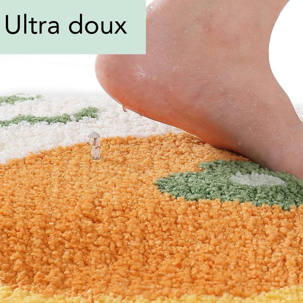 Round orange bath mat with green leaf design, ultra soft texture, foot stepping on it.