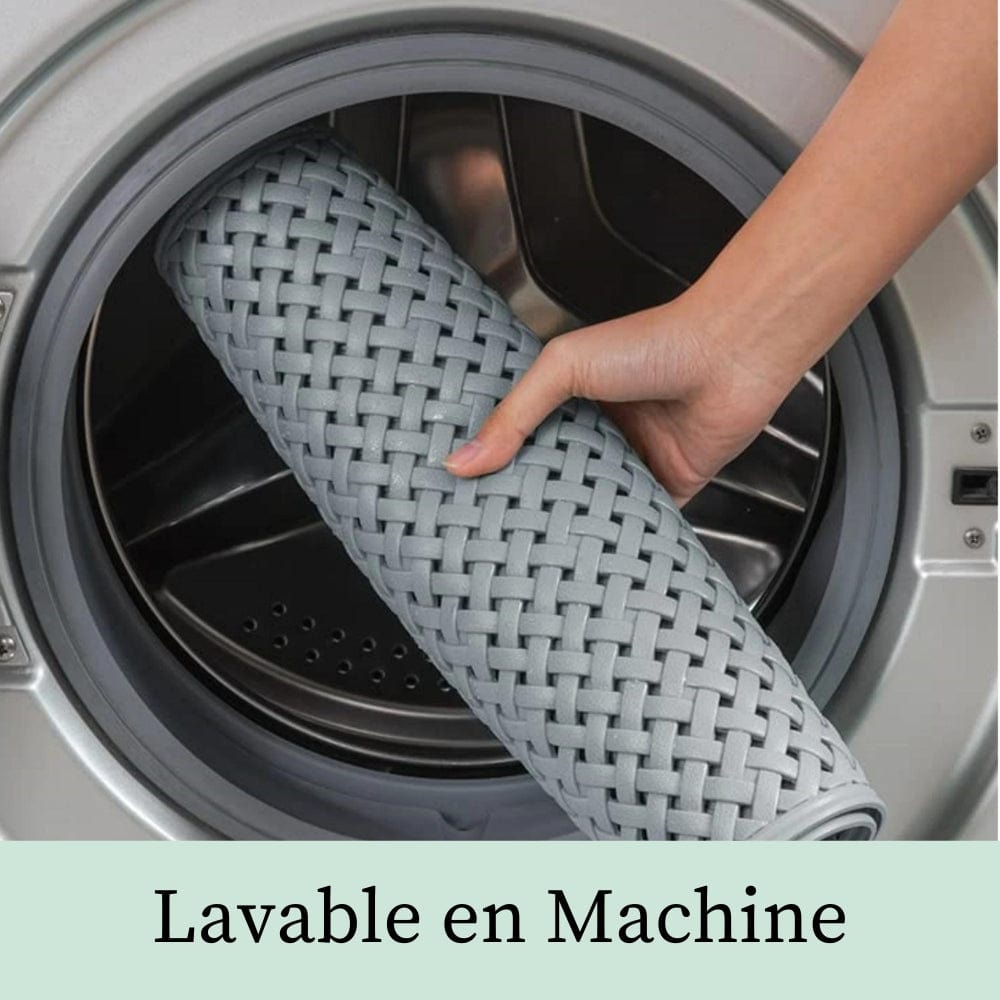 Gray woven shower bath mat being placed in washing machine for easy cleaning.