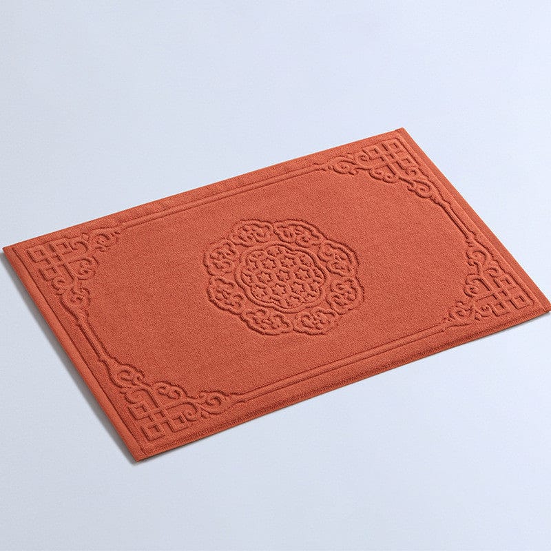 Thick cotton bath mat with intricate floral embroidery in terracotta.